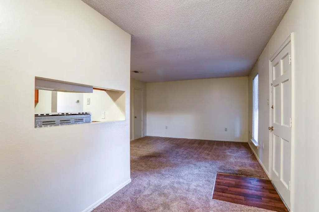 A room with a carpeted floor and a wooden floor leading to a door.